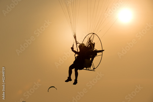Silhouette paraglider under play paramotor extreme sport, transportation fly on sky with sunlight sky background.