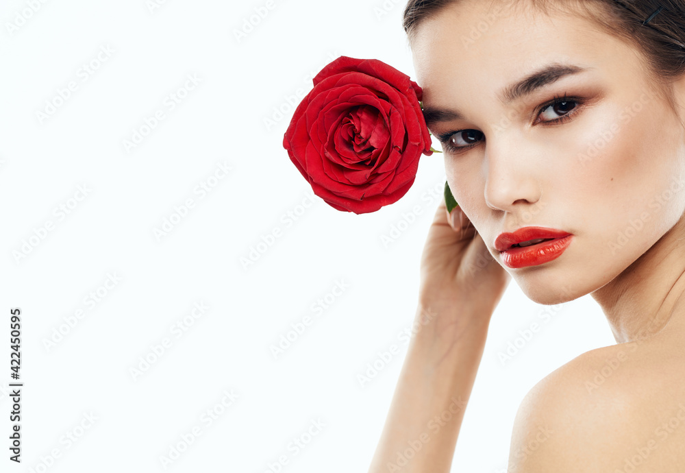 Female portrait with red flower on light background cropped view of naked shoulders Female portrait with red flower on light background cropped view of naked shoulders