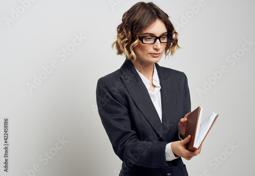 Business woman in a classic suit with a book in her hands on a light background indoors