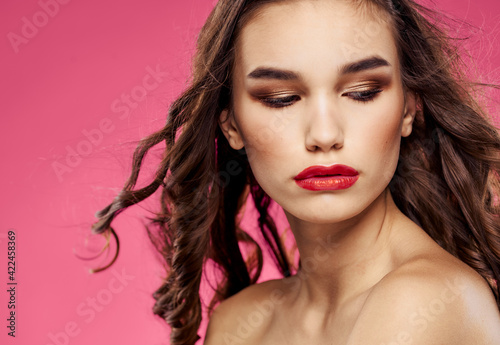 Woman with closed eyes on a pink background evening makeup red lips
