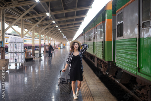 Woman traveler walking with luggage at Bangkok train station, Thailand.
