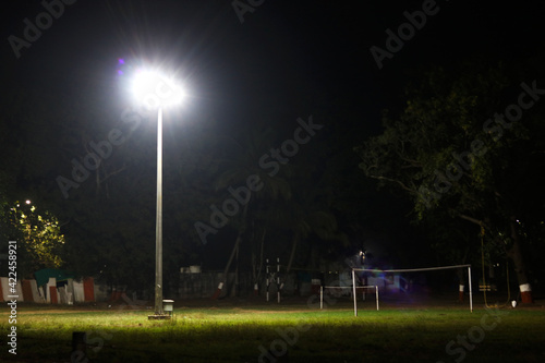 halogen lamp glowing on pole in empty ground at night