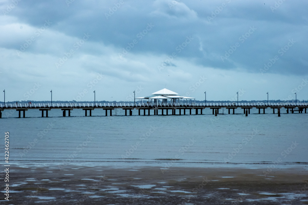 Shorncliffe Pier on an overcast day. Side view of the pier with cloudy sky.