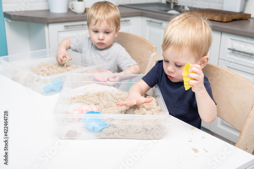 two blonde boys twins play with kinetic sand at home. Creative play for kids