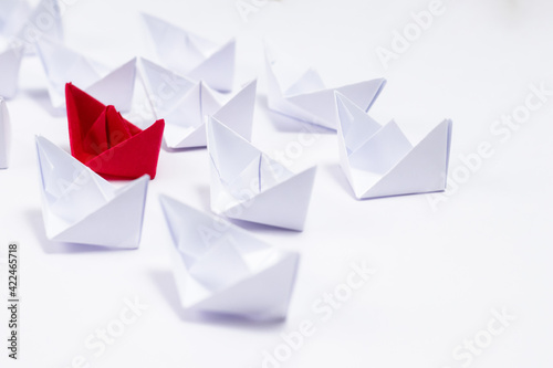 A red paper boat between white boats showing Unique and leadership concept.