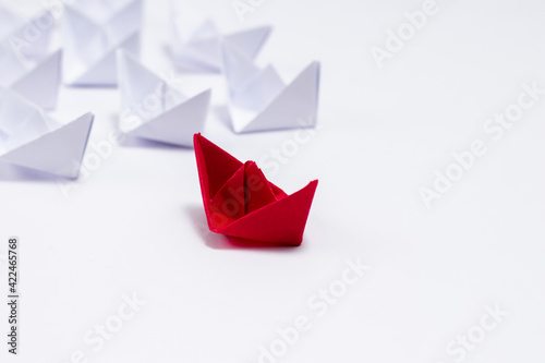 A Red paper boat with white boats following it in Leadership concept.
