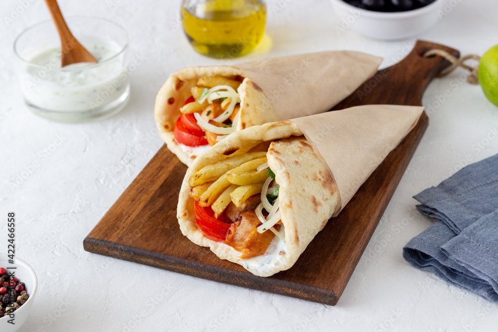 Greek dish gyros with chicken, french fries, tomatoes, onions and pita. Greek cuisine.