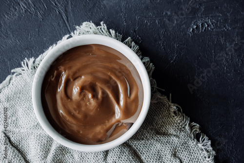 homemade chocolate pudding in white porcelain plate on dark background. homemade recipes for children. food content. chocolate paste texture . selective focus photo