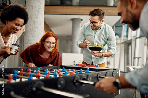 Happy business team playing table football and having fun on a break at work.