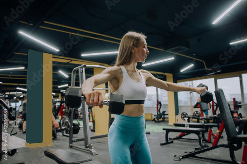 Athletic women training chest on a simulator at gym