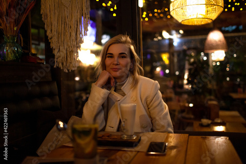 Beautiful woman sit in night cafe and eat fast cafe and dink coffee in evening.