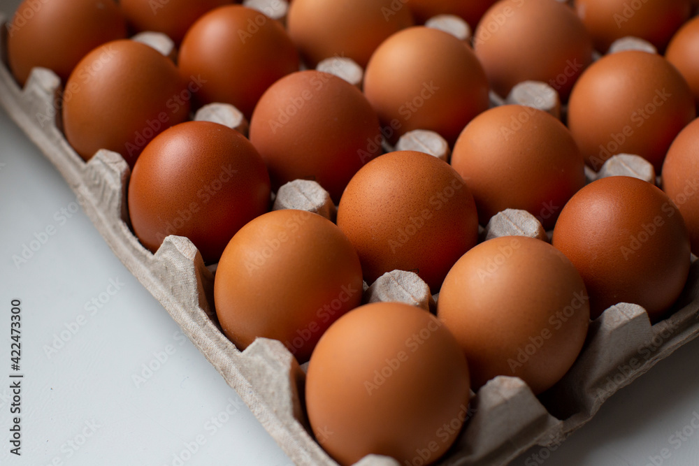Rural, raw and fresh eggs in cartoon egg box tray, close-up with soft and select focus and isolated copy space. Rural, raw and fresh eggs in cartoon egg box tray, close-up with soft and select focus and isolated copy space.