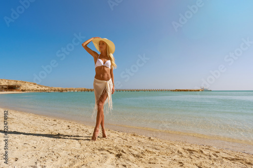 Young fashion woman standing near water on the beach