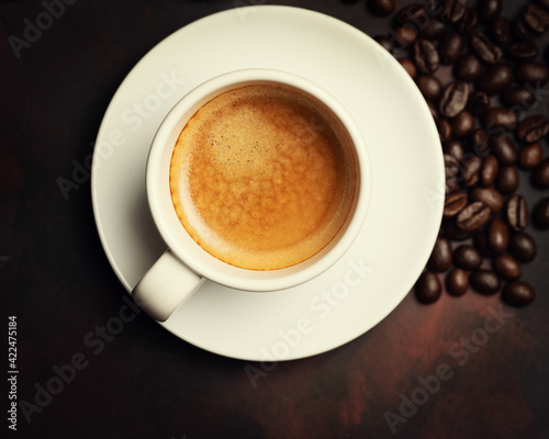 White cup of coffee and coffee bean on dark background. Copy space. Top view.