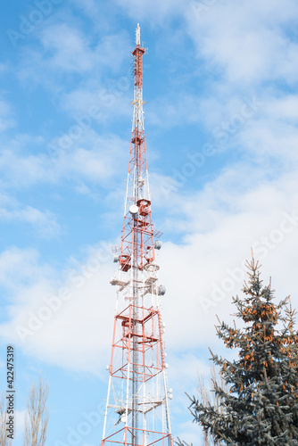 Television radio tower in the city against the backdrop of the cloudy sky. Satellite broadcasting, telecommunications. Vertical photo