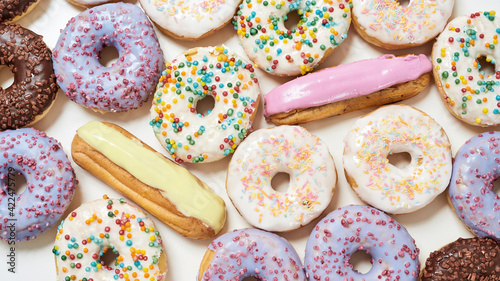 Cuadro en lienzo Top view of various delicious sweets, colourful round glazed donuts with sprinkl