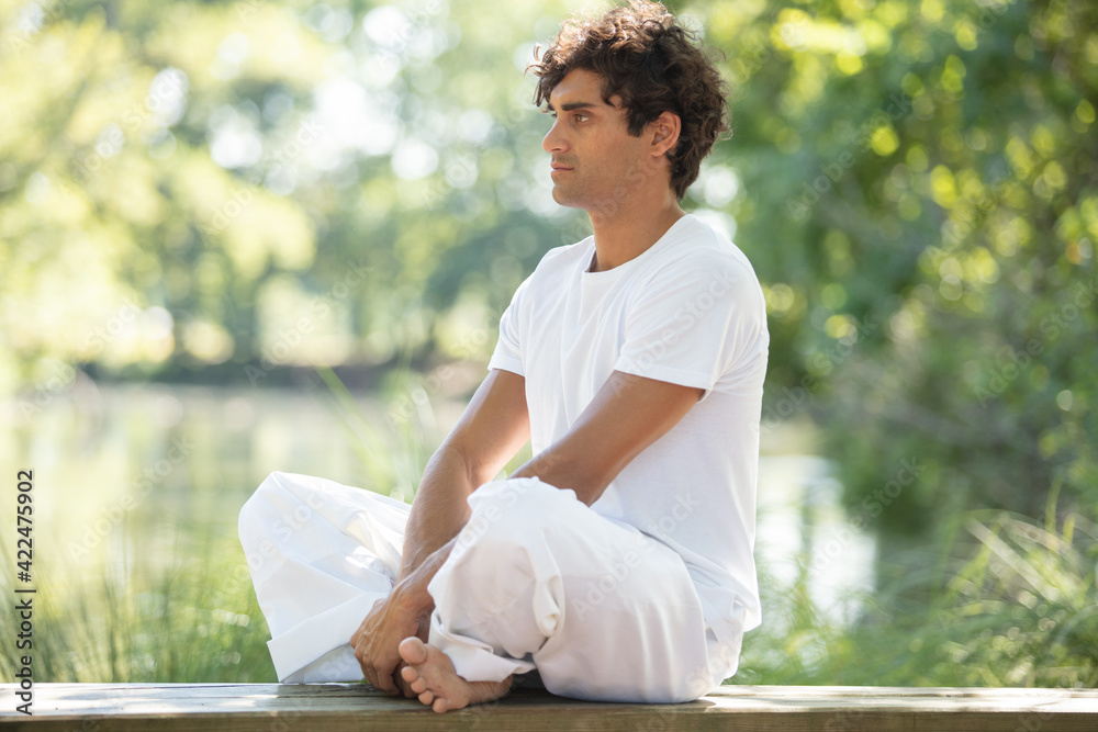 man sitting on jetty with legs crossed man sitting on jetty with legs crossed