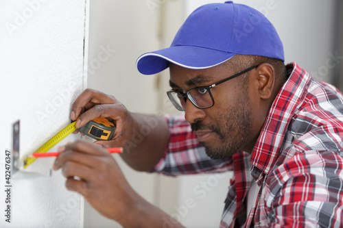 concentrated man measuring the wall with a measuring tape