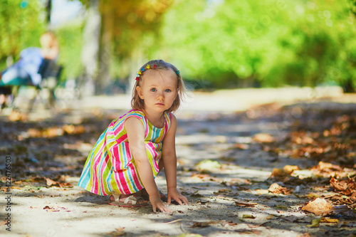 Bild auf Leinwand Cute little toddler girl squatting on her haunches on the playground