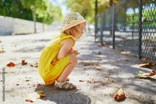 Quadro su tela Cute little toddler girl squatting on her haunches on the playground
