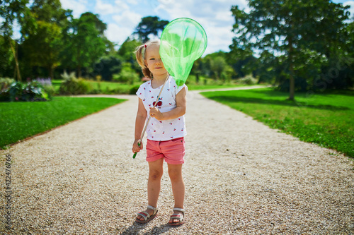 Adorable toddler girl playing with butterfy net outdoors on a summer day photo