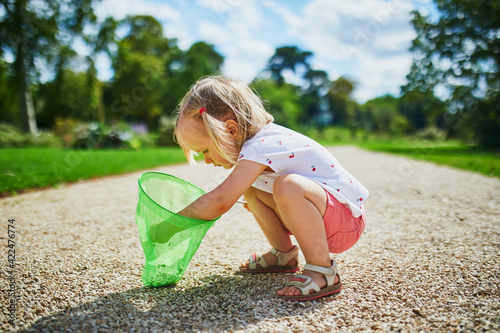 Adorable toddler girl playing with butterfy net outdoors on a summer day photo