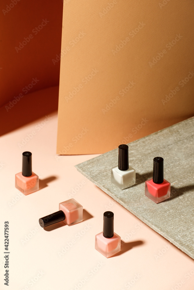 Set of nail polish bottles neutral natural colors on brick podium on beige background. Concept of pallete for french manicure, trendy modern stone platform for presentation of products