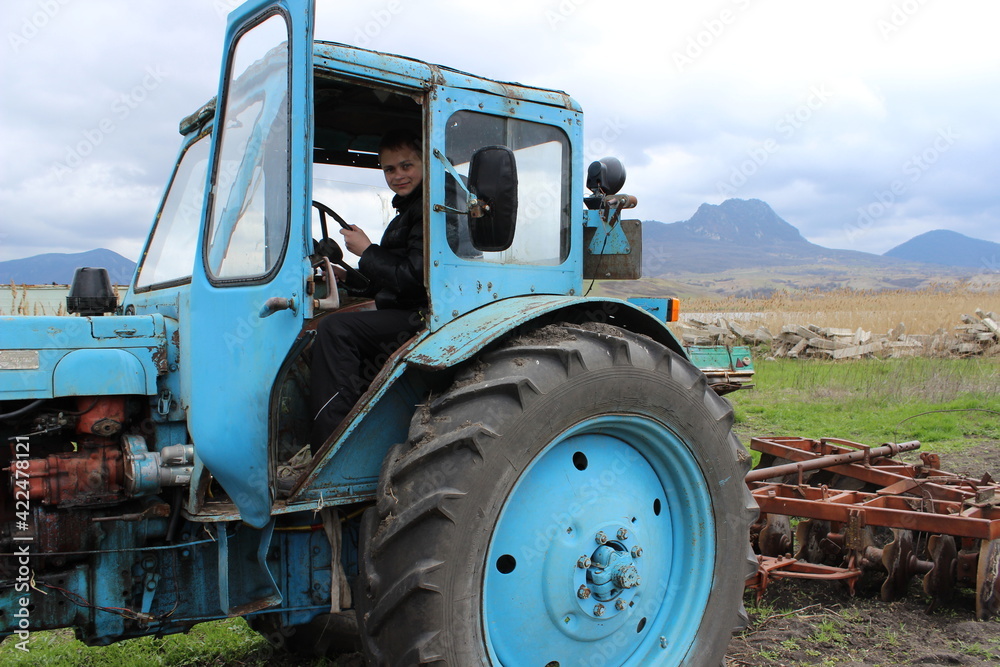 Fototapeta premium A large old blue tractor with plows field in the fall.