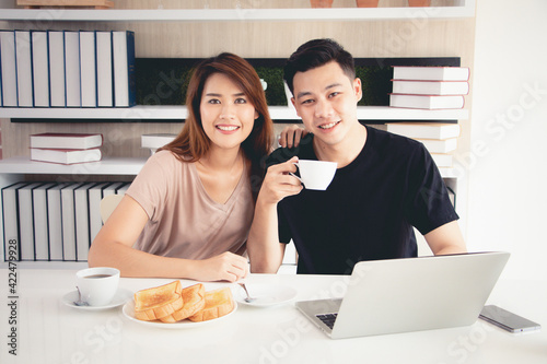 Beautiful and happy asian couple smiling while having breakfast and drinkling coffee at home in the morning together. Concept of good relationship, enjoying married life and lifestyle. Vintage style.