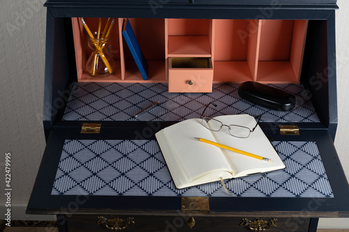 Fotografie A open bureau writing desk with notebook and pencil.