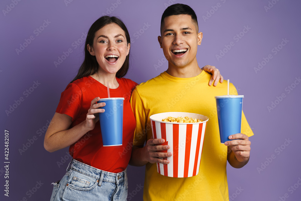 Happy couple drinking soda and eating popcorn while watching movie