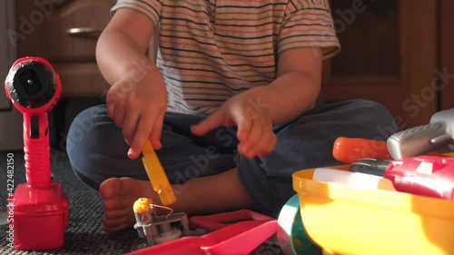 Caucasian boy is playing on the floor with mechanic toys simulating the repair of something photo