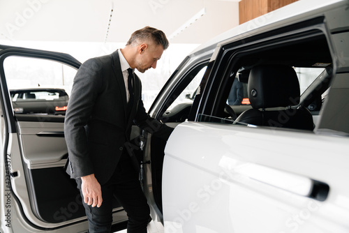 Mature white man choosing and examining car in showroom © Drobot Dean
