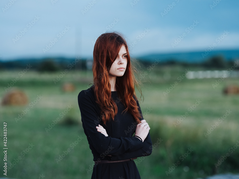 red-haired woman in black dress in nature outdoors