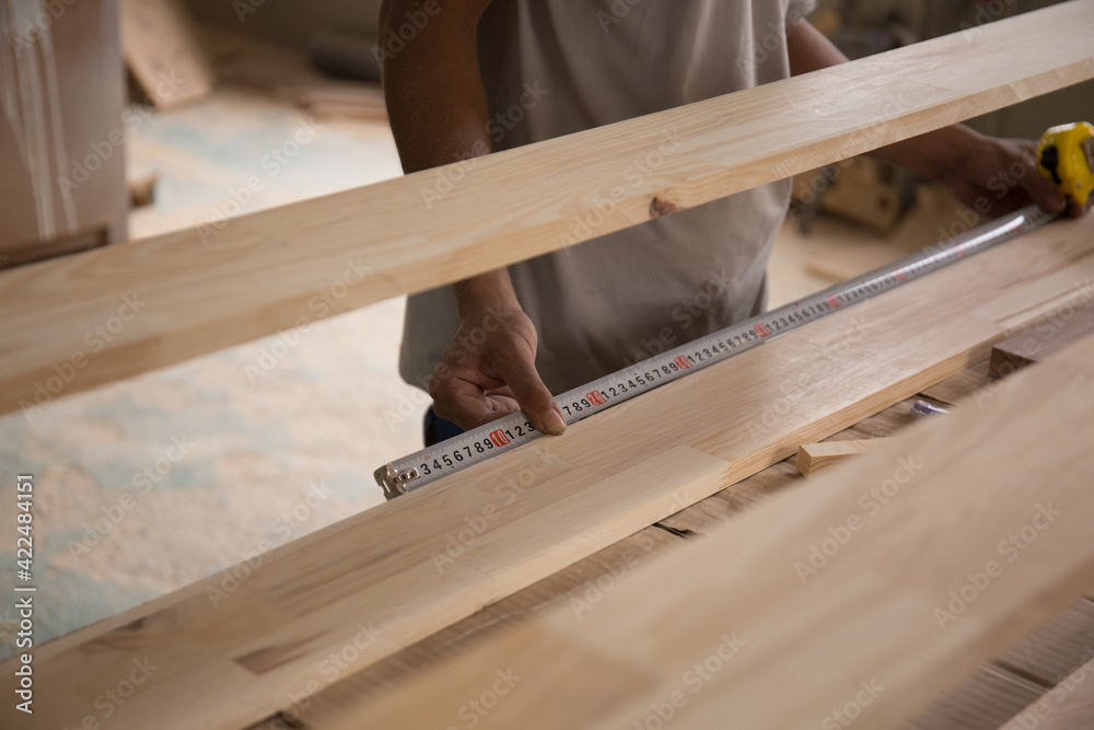 Carpenter measuring wooden board with ruler with scale in workshop. Joinery work on the production of wooden furniture. Small Business Concept