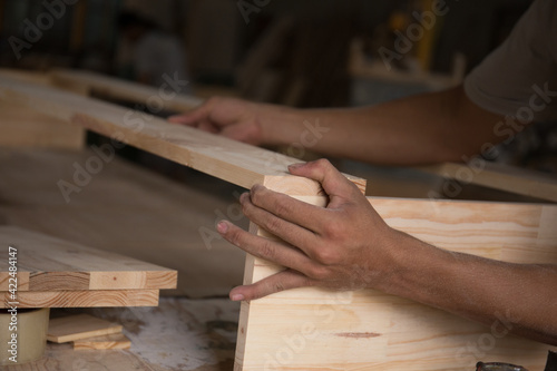 Close-up of hand carpenter joining wood planks at an angle. Man working in workshop. Joinery work on the production and renovation of wooden furniture. Small Business Concept