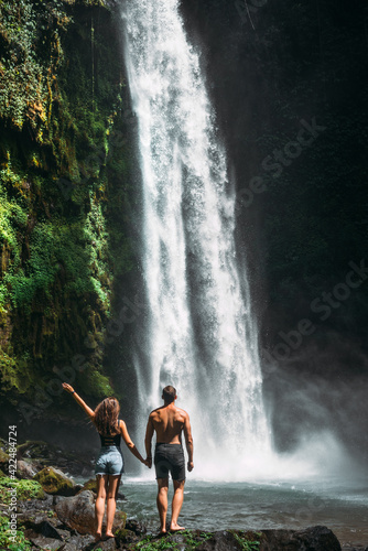 Couple at the waterfall  rear view. Couple on vacation in Bali. Honeymoon trip. A couple in love travels the world. Vacation on the island of Bali. Tourists in Bali. Copy space