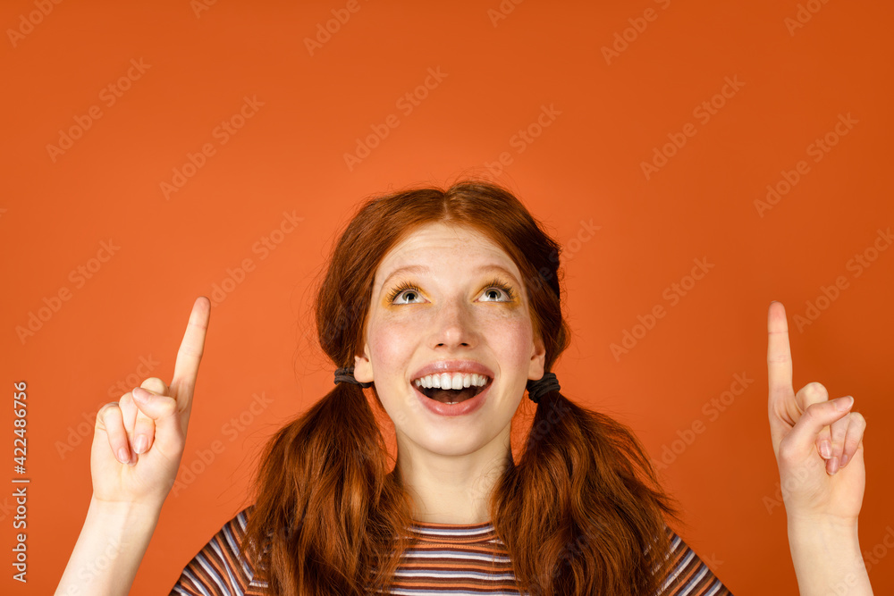Ginger cheerful woman with tails smiling and pointing fingers upward Ginger cheerful woman with tails smiling and pointing fingers upward