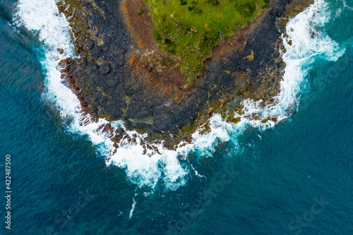 Aerial top down shot of the blue ocean surf waves crashing on the rocks at the edge Green Island at Cunjurong Point New South Wales Australia