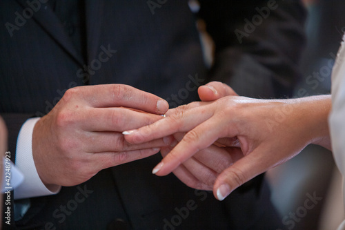 Close up of loving bride and groom putting a beautiful wedding ring to the beloved partner, marry me concept. High quality photo