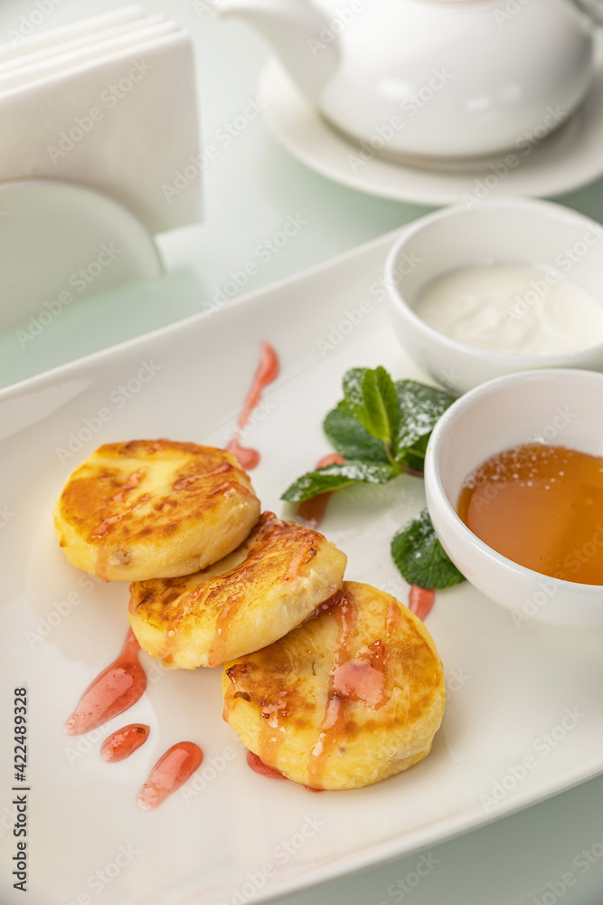 Cheesecakes with sour cream and honey on a white table
