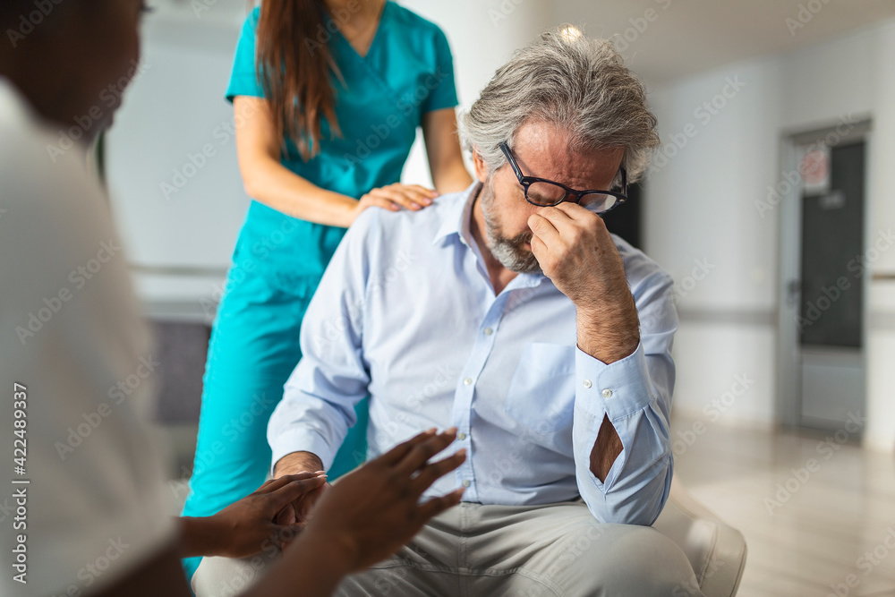 Female doctor reassuring supporting senior adult patient in hospital. Kind caring young woman nurse or caregiver helping older retired man talking, giving comfort, expressing care concept. Female doctor reassuring supporting senior adult patient in hospital. Kind caring young woman nurse or caregiver helping older retired man talking, giving comfort, expressing care concept.