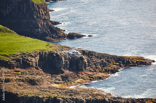 Helicopter flying over mykines atlantic cliffs in Faroe islands. Denmark photo
