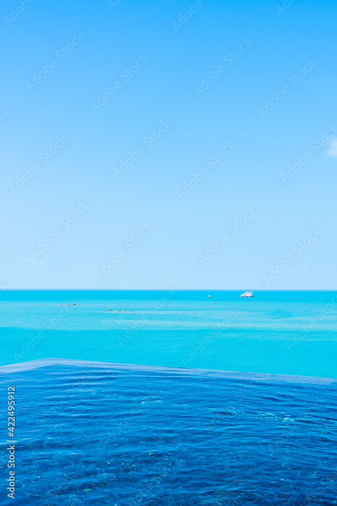 Obraz premium Beautiful private infinity outdoor swimming pool with sea ocean white cloud and blue sky view