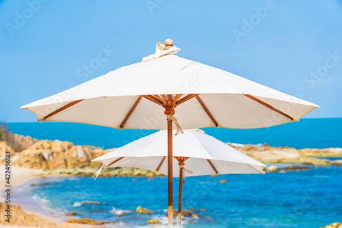 Beautiful tropical beach sea with umbrella and chair around white cloud and blue sky © siraphol