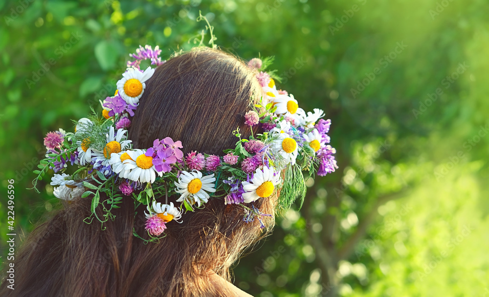 Naklejka premium girl in summer solstice wreath, sunny day outdoor. rear view of woman with brown hair and wildflowers wreath. pagan Slavic ceremony on Midsummer
