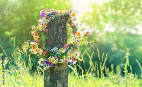 rustic wildflowers wreath on sunny meadow. Summer Solstice Day, Midsummer concept. floral traditional decor. pagan witch traditions, wiccan symbol and rituals.
