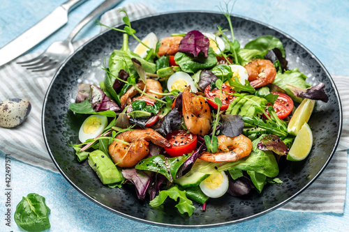 Fresh salad plate with cherry tomatoes, cucumber, avocado, eggs and smoked shrimps, mixed greens. Healthy food. Clean eating. Food recipe background. Close up