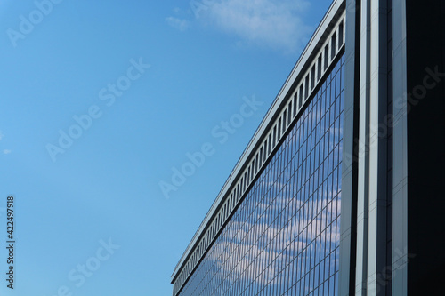 Abstract business background. Glass windows of an office building against the blue sky with space for text.