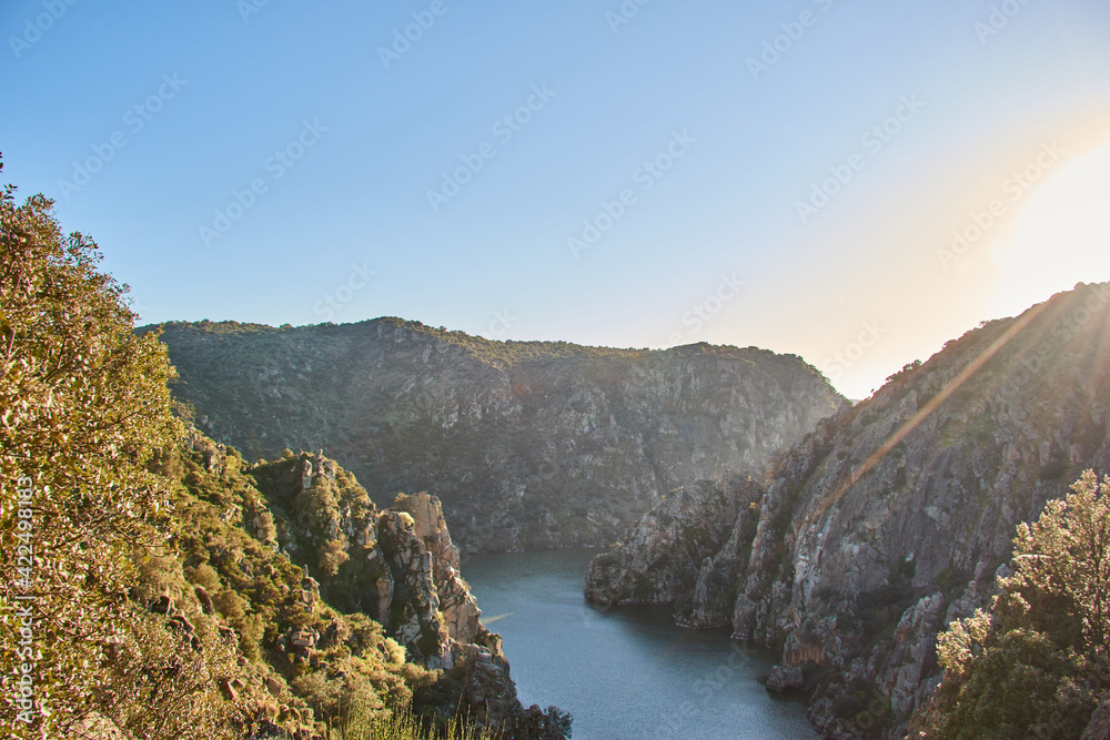Three rocky mountains with cliffs and a river at sunset. Three rocky mountains with cliffs and a river at sunset.